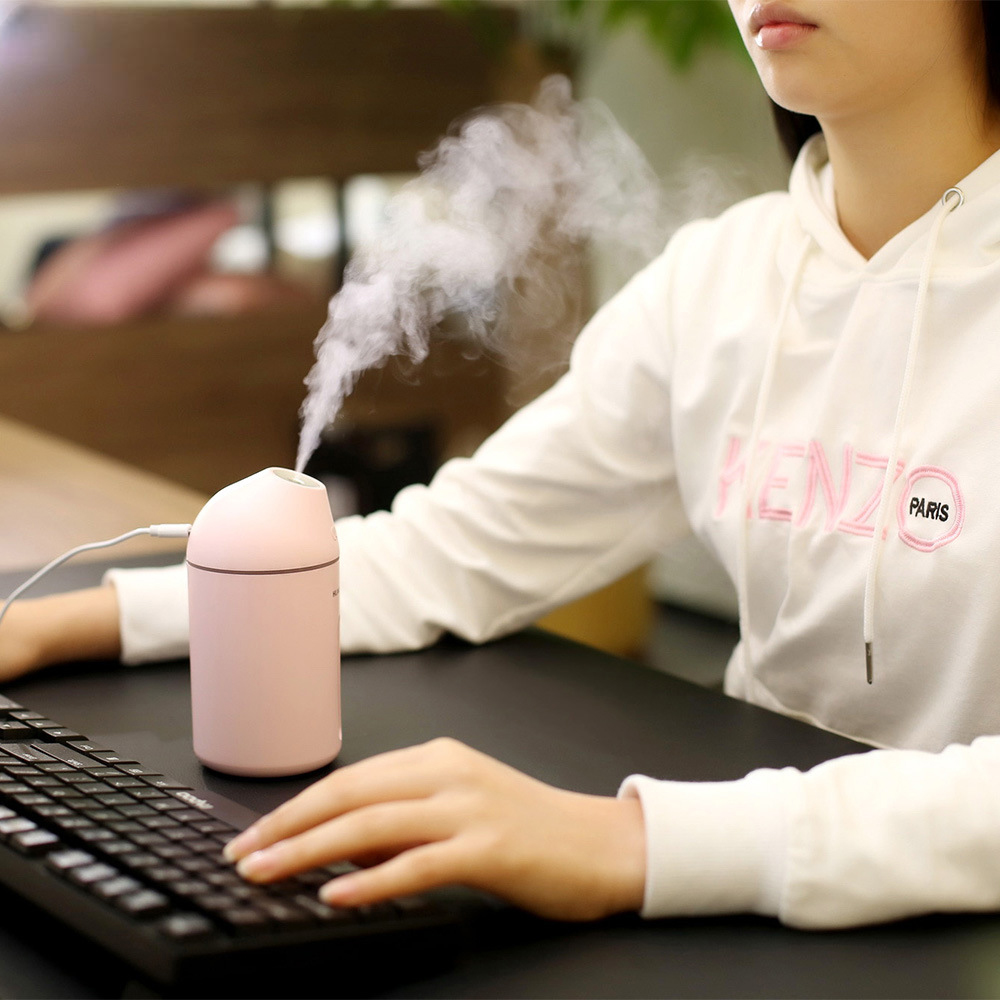 AromaDrive 300ml USB Diffuser in use, emitting mist while a user types on a keyboard.